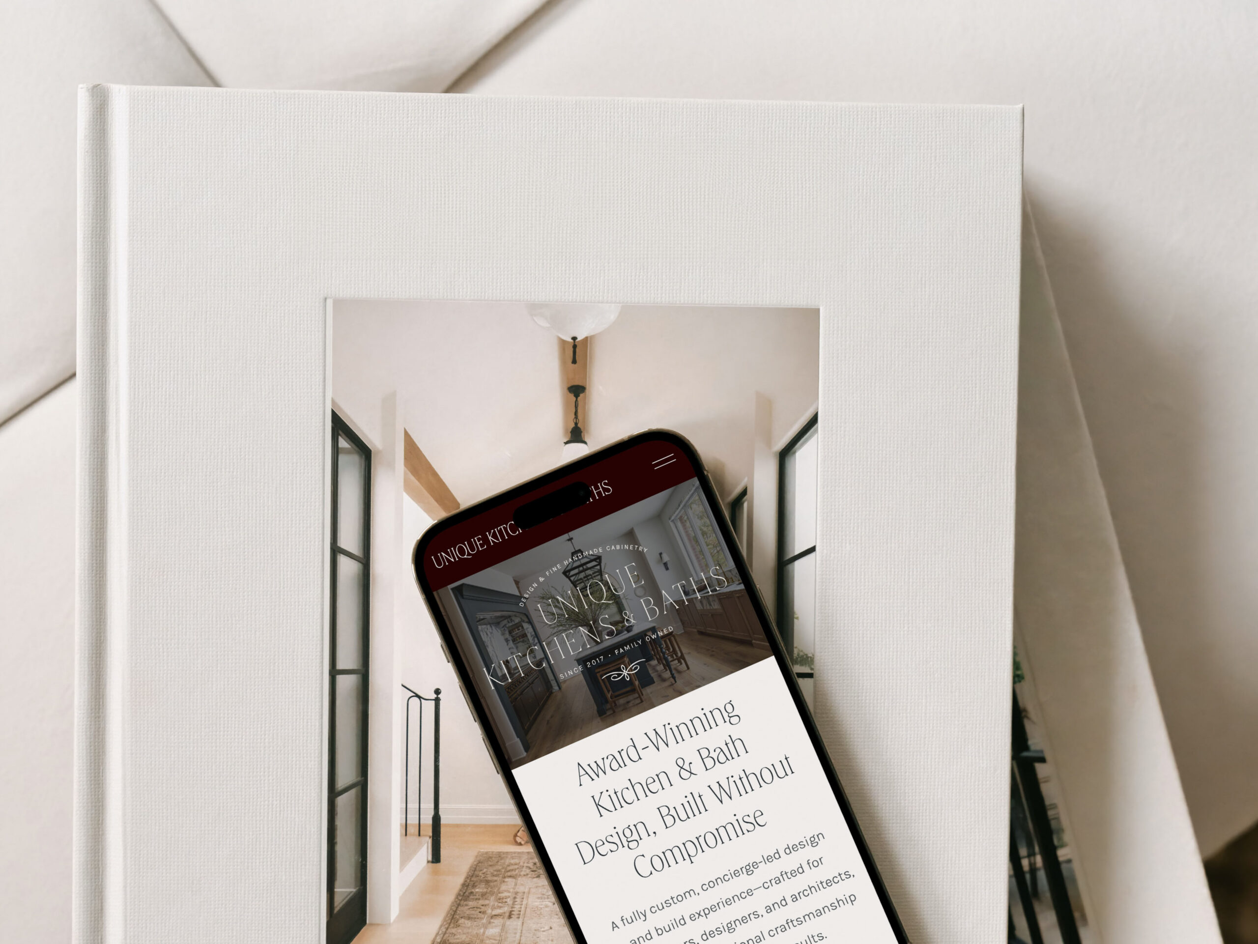 Smartphone displaying a luxury interior designer website placed on stacked design books, highlighting a seamless mobile user experience.